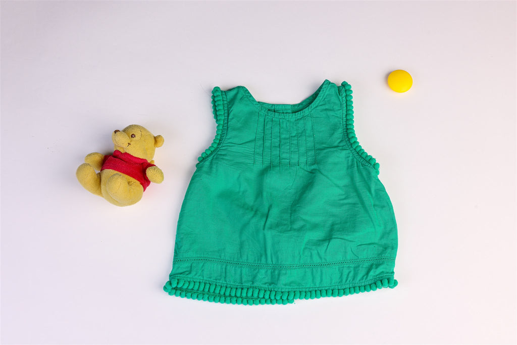 Green top with pompoms on the sleeves and hem